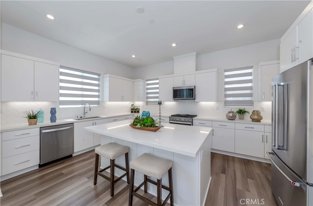 1403 West Bushell Street Anaheim, CA 92805 - Photo 9 of 31 a kitchen with white cabinets and wooden floor
