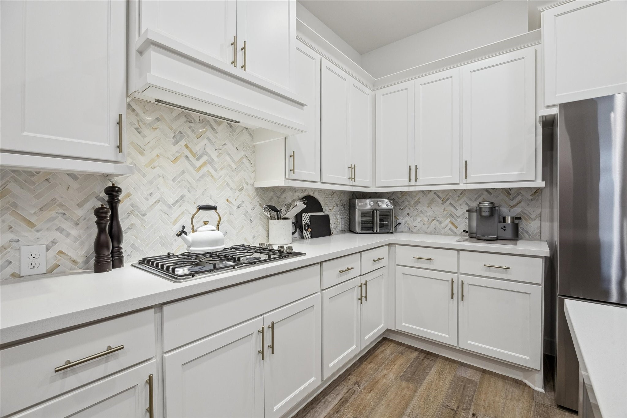 9823 Chapman Trail Manvel, TX 77578 - Photo 11 of 47 The attractive finishes continue with a herringbone tile backsplash and handsome oversized hardware, creating a bright and inviting space for cooking and entertaining.