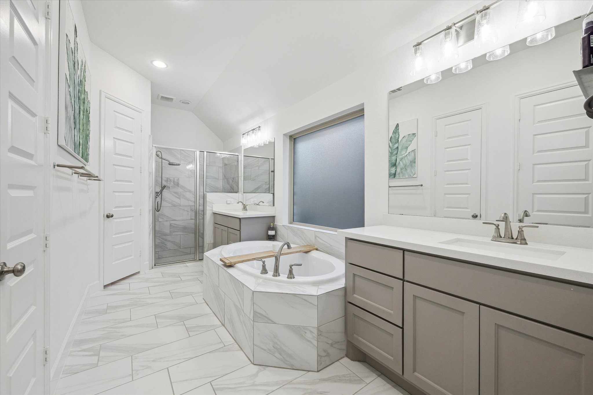 9823 Chapman Trail Manvel, TX 77578 - Photo 20 of 47 This modern bathroom features a spacious layout with a large soaking tub, separate glass-enclosed shower, dual sinks with ample counter space, and sleek cabinetry. The neutral color palette and contemporary finishes create a serene and inviting atmosphere.