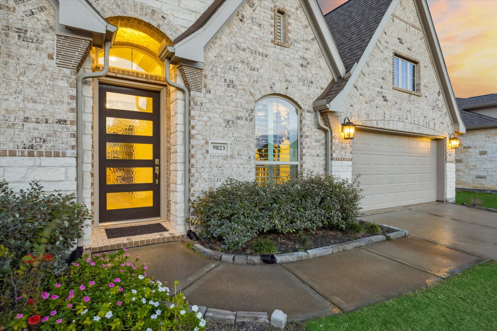 9823 Chapman Trail Manvel, TX 77578 - Photo 4 of 47 This home features a welcoming facade with a modern front door, attractive brickwork, and warm exterior lighting, creating a cozy and inviting entrance.