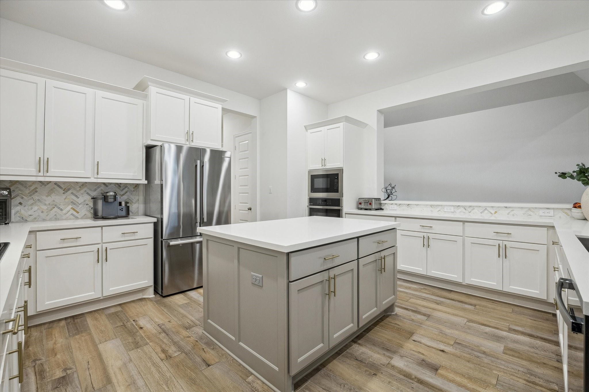 9823 Chapman Trail Manvel, TX 77578 - Photo 10 of 47 The modern kitchen features sleek white cabinetry and quartz countertops. The center island is soft gray in color and offers uninterrupted prep and serving space. The stainless steel French door refrigerator will stay for the new homeowner.