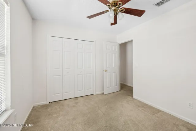 an empty room with a window and a fan