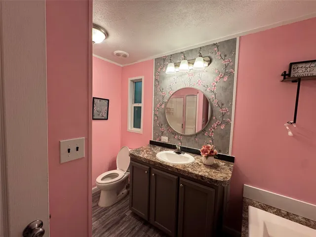 a bathroom with a granite countertop toilet sink and mirror