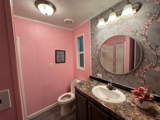 a bathroom with a granite countertop toilet sink and mirror