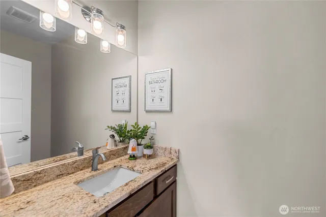 a bathroom with a granite countertop sink and a mirror