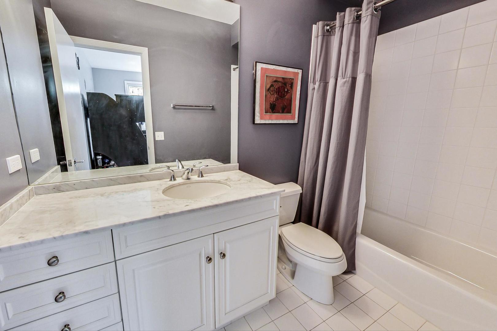 1137 West Monroe Street Chicago, IL 60607 - Photo 23 of 33 a bathroom with a sink a toilet a mirror a vanity and shower