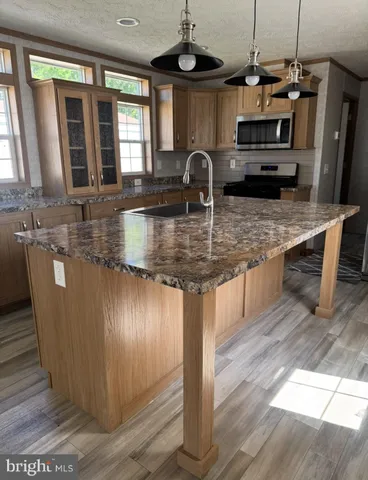 a kitchen with stainless steel appliances granite countertop a sink a counter space and a window