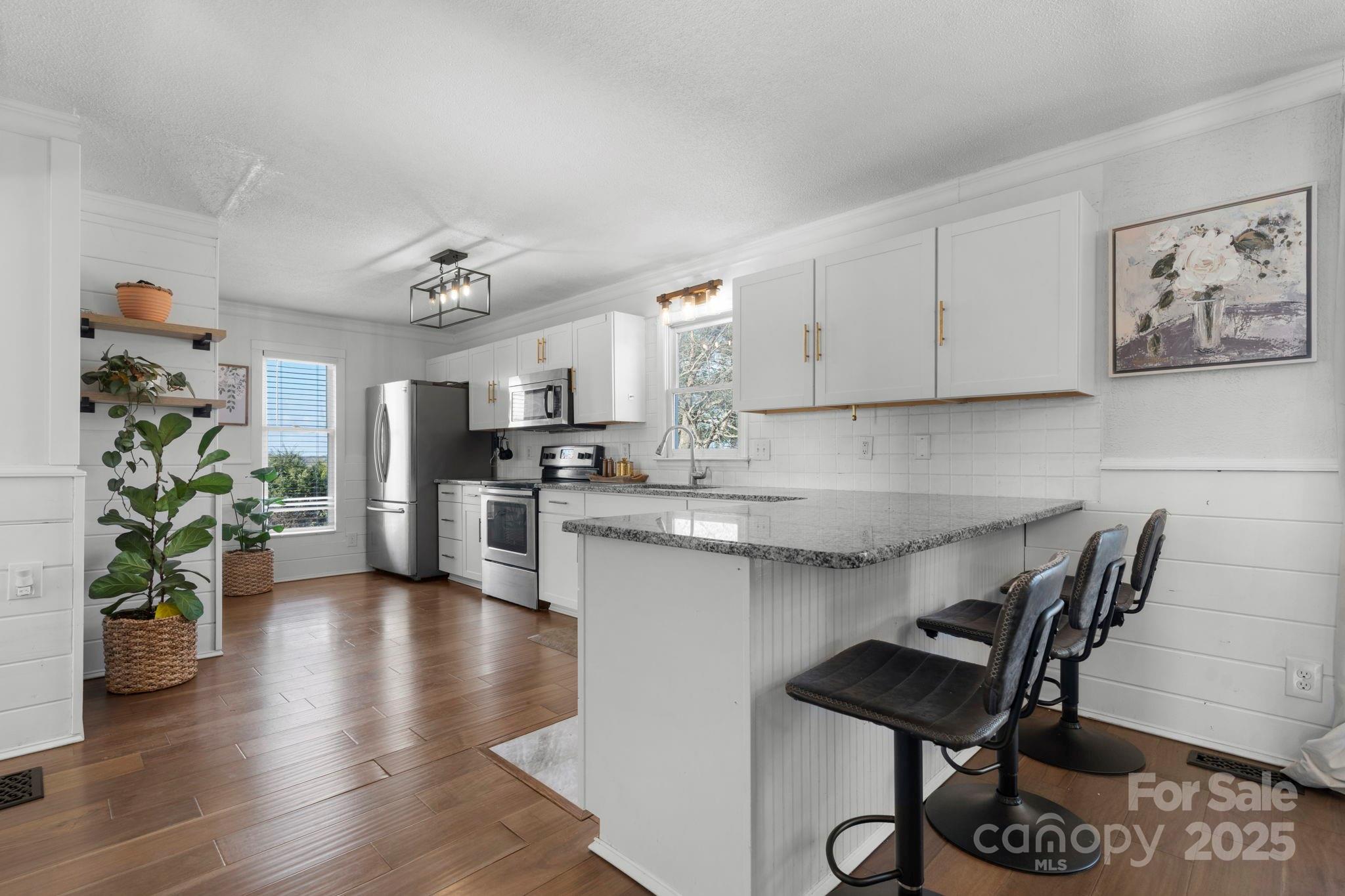 20 Meandering Way Granite Falls, NC 28630 - Photo 22 of 39 a kitchen with stainless steel appliances granite countertop a stove top oven a sink a dining table and chairs with wooden floor