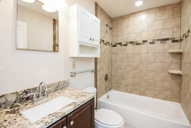 a bathroom with a granite countertop sink toilet and shower