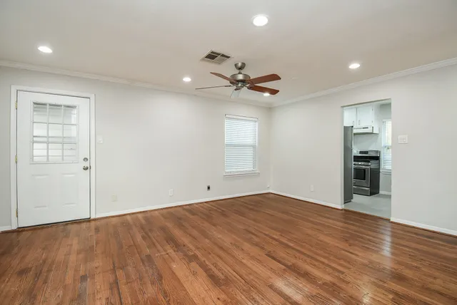 a view of an empty room with a window and a kitchen
