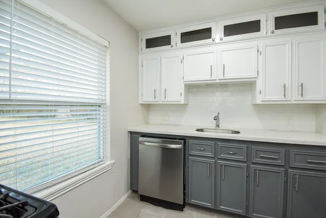 a kitchen with stainless steel appliances granite countertop white cabinets and a window