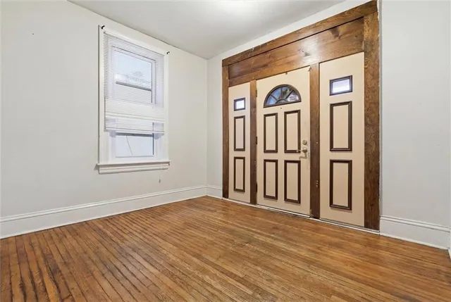 an empty room with wooden floor closet and windows