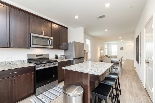 a kitchen with a stove a sink a microwave a refrigerator and chairs