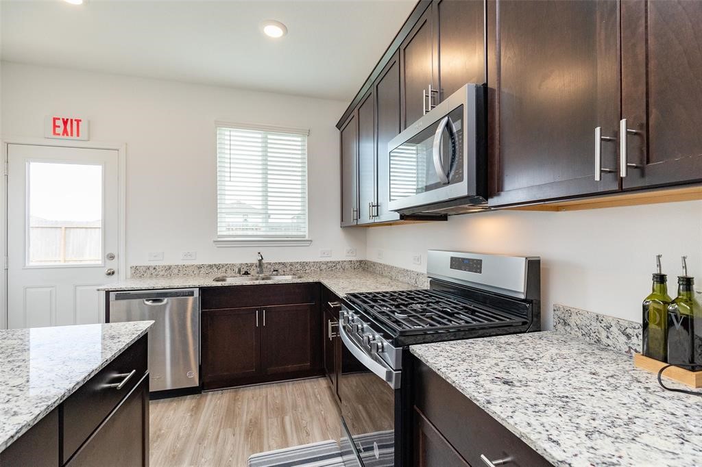 23631 Simmental Road Hockley, TX 77447 - Photo 9 of 22 a kitchen with granite countertop stainless steel appliances and sink