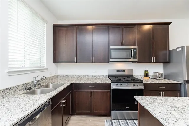 a kitchen with granite countertop cabinets stainless steel appliances and sink