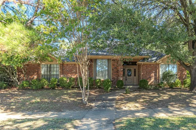 a view of a brick house with a large windows and large trees