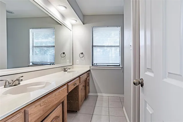 a bathroom with a double vanity sink a mirror and a bathtub