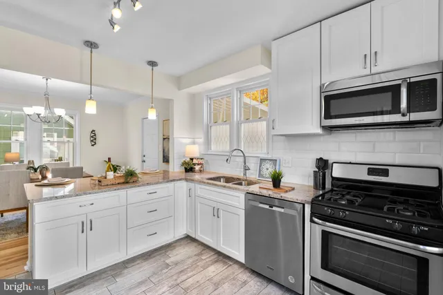 a kitchen with stainless steel appliances white cabinets granite counter tops and a wooden floors