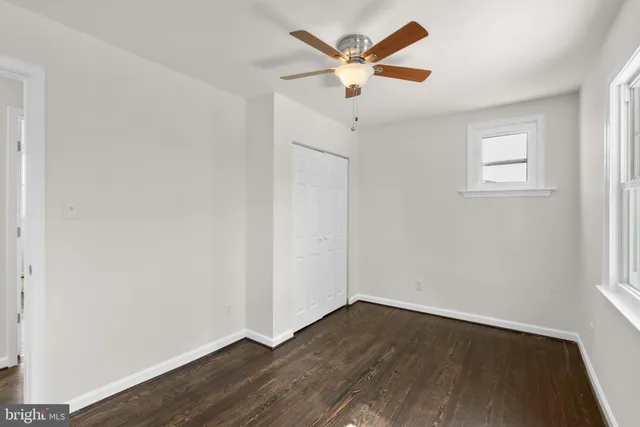 an empty room with wooden floor and ceiling fan