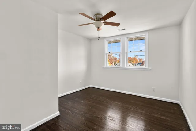 an empty room with wooden floor and ceiling fan