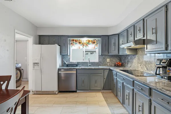a kitchen with stainless steel appliances granite countertop a refrigerator sink and stove