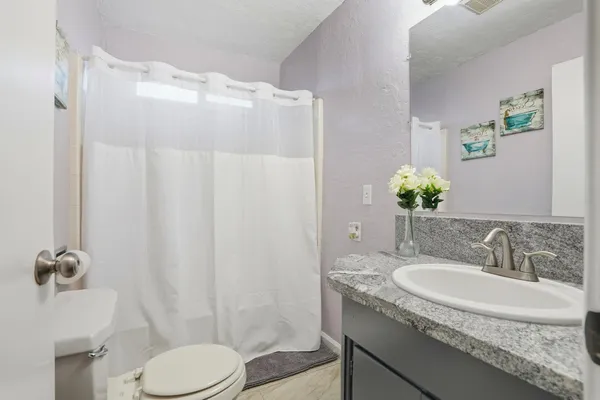 a bathroom with a granite countertop sink toilet and shower