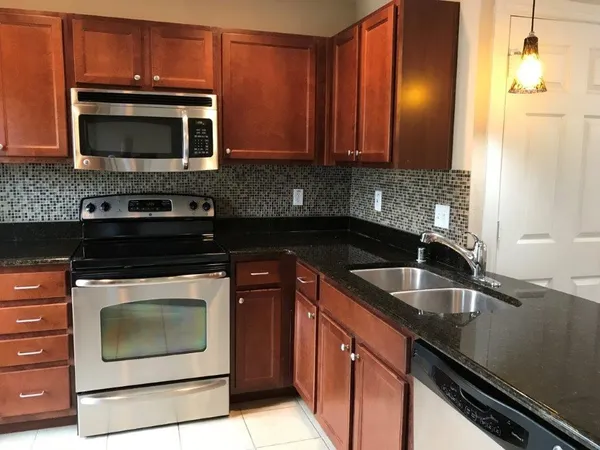 a kitchen with stainless steel appliances granite countertop a refrigerator a stove a sink and a microwave