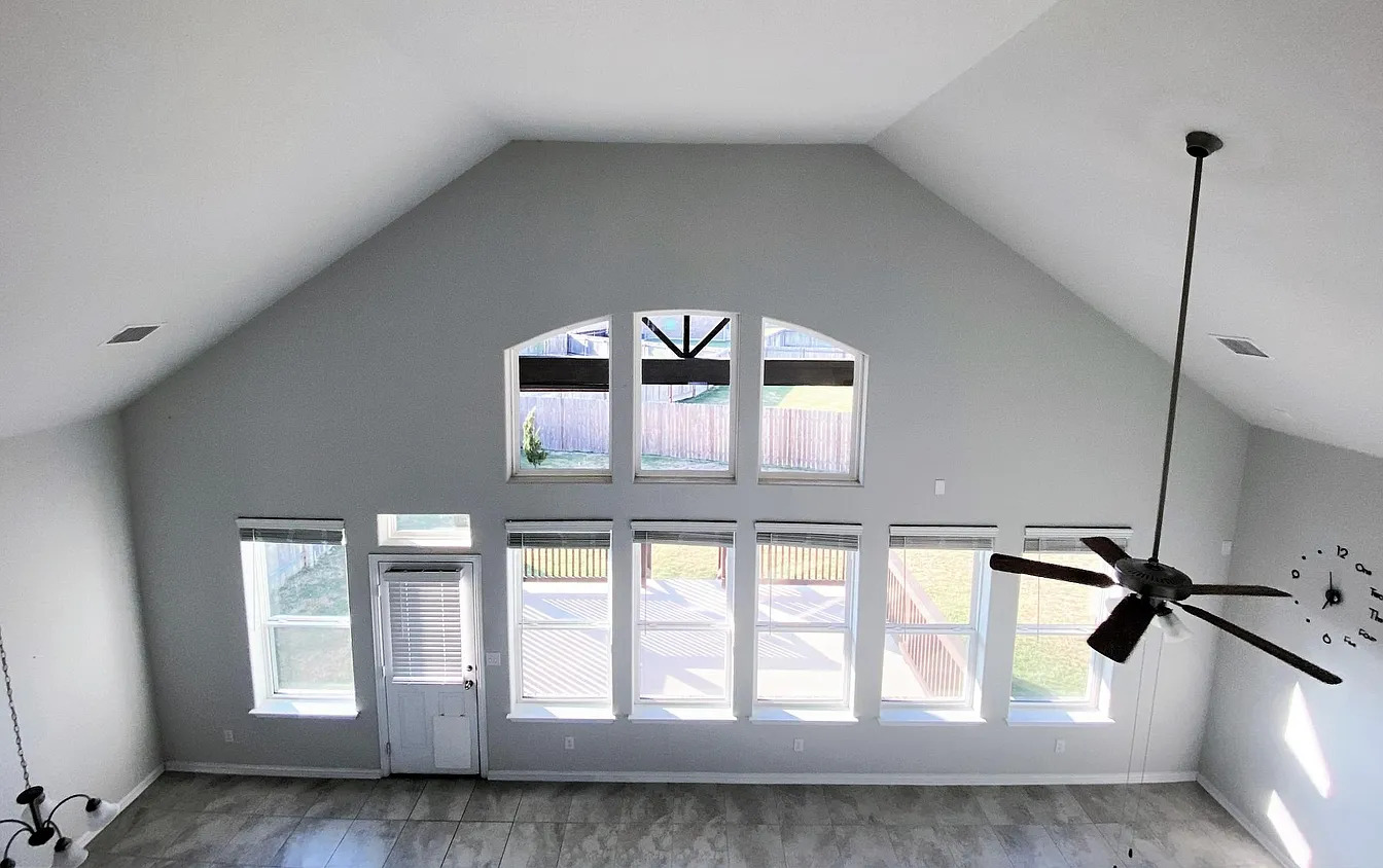 717 Paper Daisy Path Leander, TX 78641 - Photo 2 of 7 A spacious room features soaring vaulted ceilings and abundant natural light from a wall of windows overlooking the backyard.