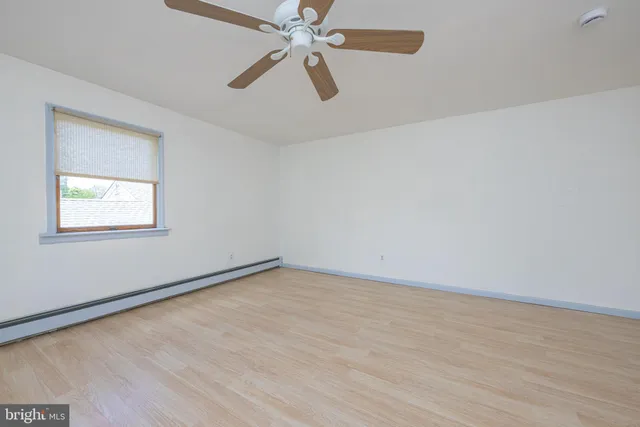 an empty room with a window and a fan