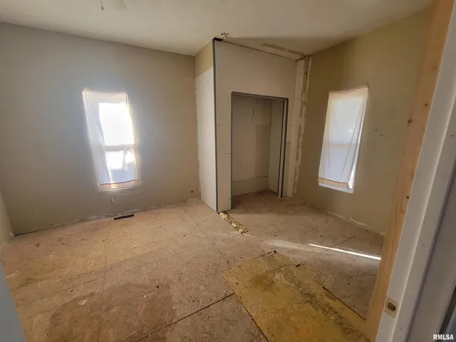 an empty room with windows and fan