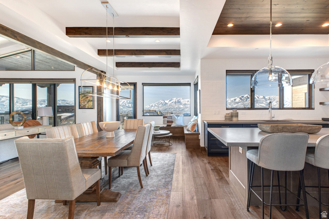 1282 Chimney Rock Road, Unit 344 Heber City, UT 84032 - Photo 13 of 55 Open-concept dining and kitchen areas featuring wood-finish flooring, exposed ceiling beams, a long dining table, a kitchen island with seating, and a built-in window seat