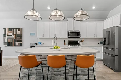 a kitchen with stainless steel appliances granite countertop a dining table chairs and a refrigerator