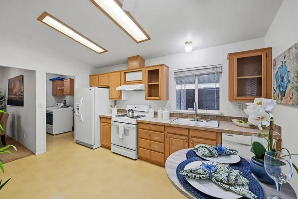 a very nice looking open kitchen with stainless steel appliances granite countertop a stove top oven a sink a dining table and chairs