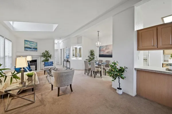 a living room with furniture a potted plant and a kitchen view