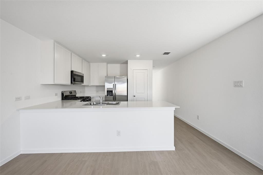 1613 Elliott Road Howe, TX 75459 - Photo 4 of 19 a large white kitchen with kitchen island a sink wooden floor and white stainless steel appliances