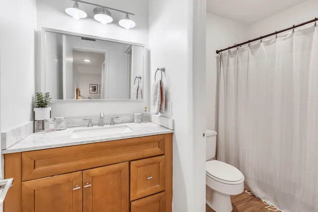a bathroom with a granite countertop sink toilet and mirror