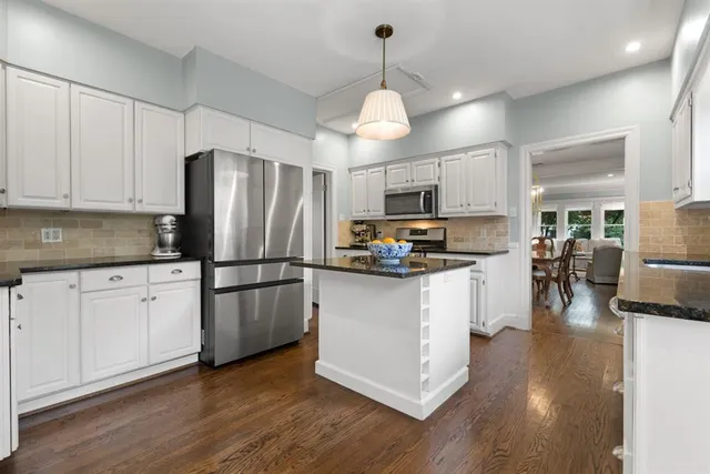 a kitchen with stainless steel appliances granite countertop a refrigerator a stove oven a sink dishwasher and a refrigerator with wooden floor