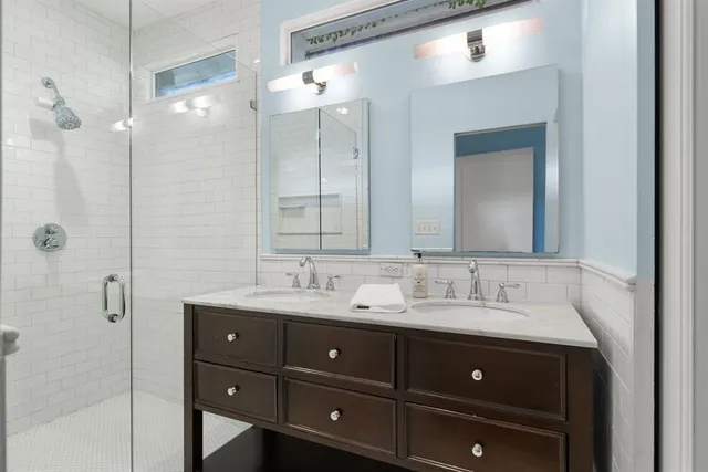 a bathroom with a double vanity sink and mirror with shower