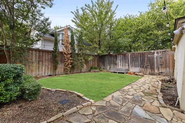 a view of backyard with large trees and wooden fence