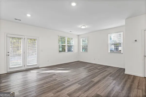 an empty room with wooden floor and windows