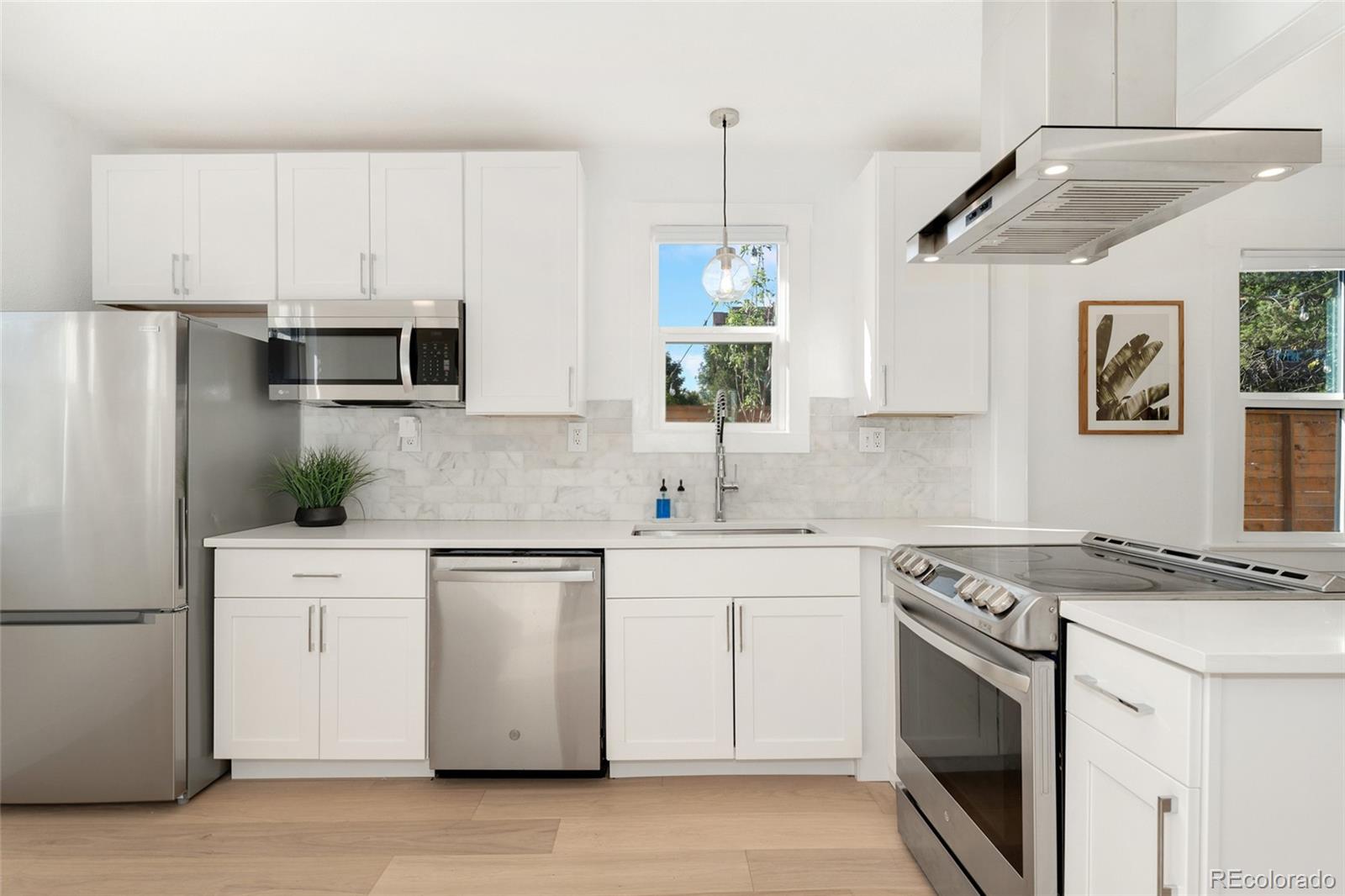 1528 Harrison Street Denver, CO 80206 - Photo 12 of 45 a kitchen with stainless steel appliances white cabinets and a stove top oven
