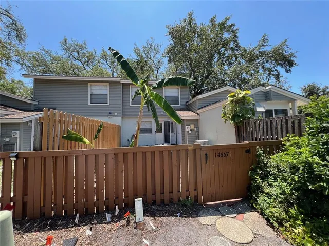 a view of a house with wooden fence and potted plants