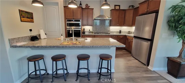 a kitchen with stainless steel appliances granite countertop furniture wooden floor and a refrigerator