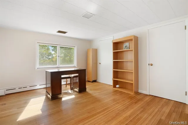 a view of an empty room with a window and wooden floor