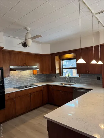 a kitchen with stainless steel appliances granite countertop a sink a stove and a wooden cabinets