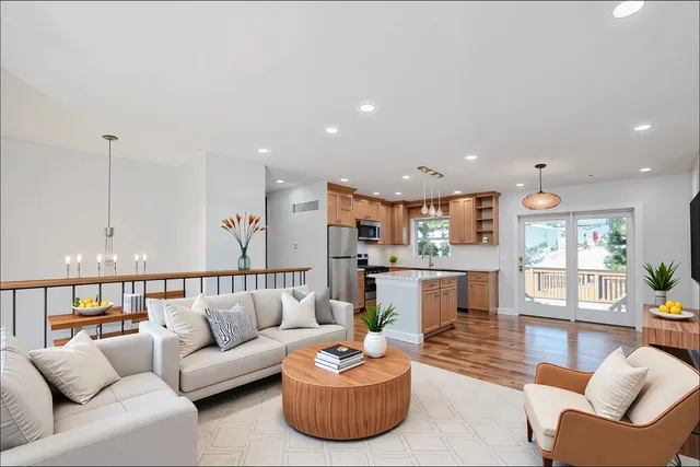 a living room with furniture kitchen view and a large window