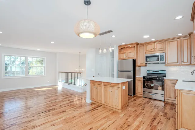 a large kitchen with stainless steel appliances granite countertop a stove oven and a wooden floors