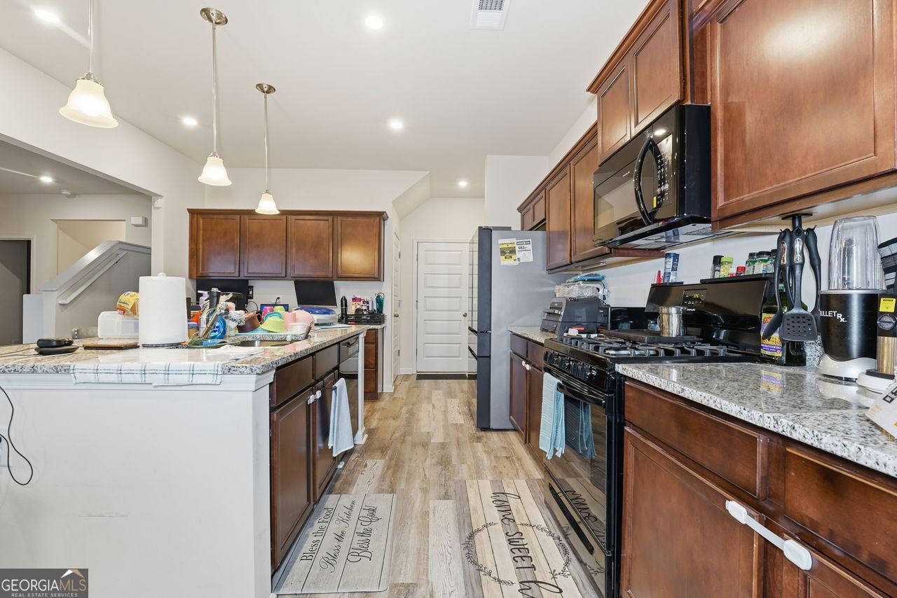 223 Malbone Street Southwest, Unit 5B Cartersville, GA 30120 - Photo 7 of 38 a kitchen with stainless steel appliances granite countertop a stove top oven a sink dishwasher a dining table and chairs with wooden floor