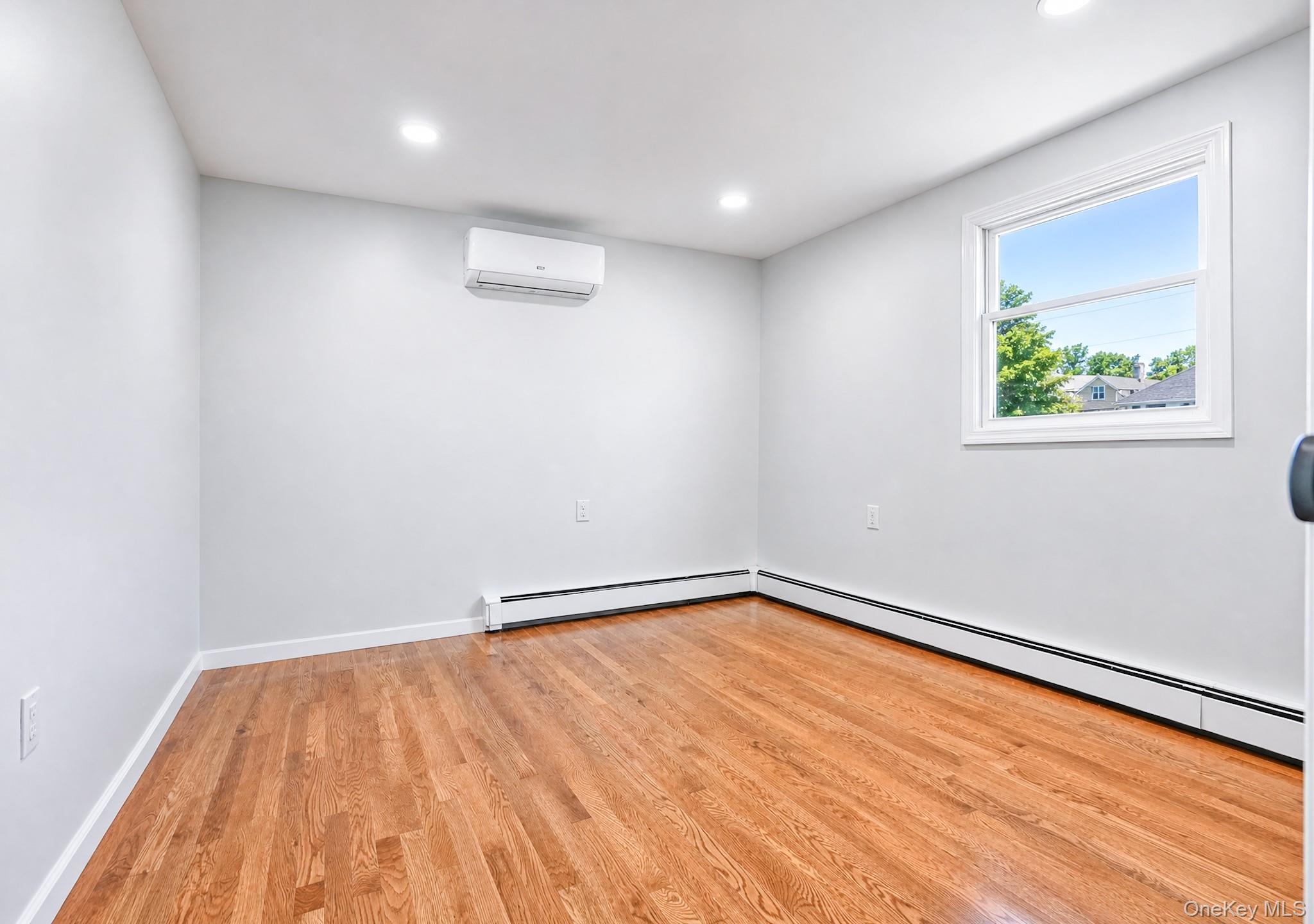 61 Cheshire Road Bethpage, NY 11714 - Photo 18 of 25 Room featuring hardwood flooring, white baseboards, recessed lighting, and a white-framed window
