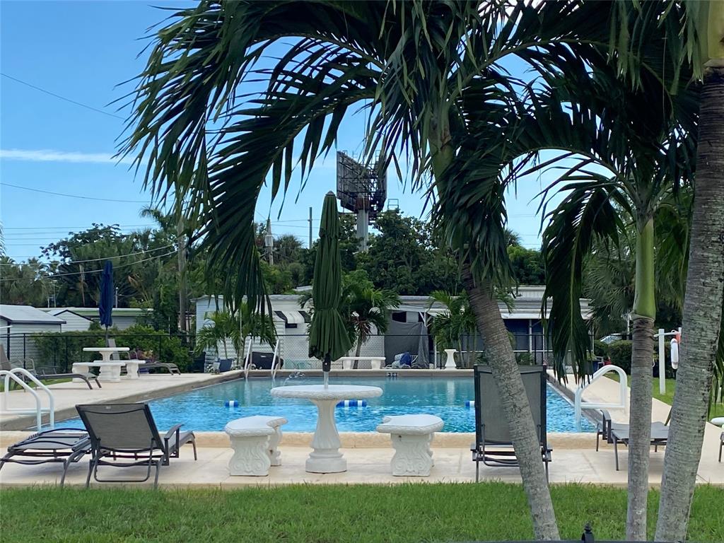 14629 Sunset Drive Delray Beach, FL 33445 - Photo 34 of 35 a view of a swimming pool with a table and chairs